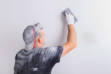 Plasterer polishing a gypsum wall. House renovation concept. - obrazy, fototapety, plakaty