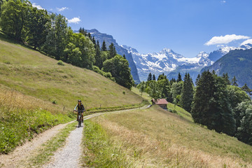 Fototapeta na wymiar nice and ever young senior woman riding her e-mountainbike below the Eiger northface, Jungfrauregion, Switzerland