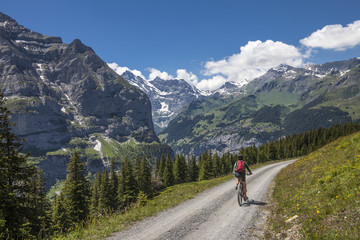 Fototapeta na wymiar nice senior woman, riding her e-mountainbike on the Lauberhorn downhill from Kleine Scheidegg to Wengen and Lauterbrunnen,Jungfrauregion,Switzerland