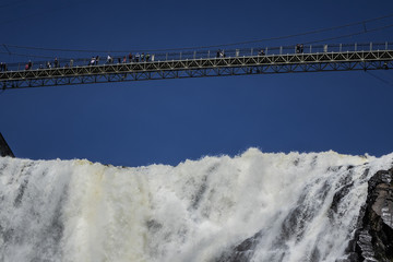 Fototapeta premium The Montmorency waterfall and bridge over waterfall. Montmorency falls, located between the river and the cliffs (10 km east of Quebec City): 275 feet (83 meters) high. Quebec, Canada, North America.