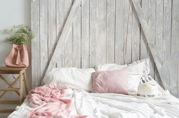 Soft home interior. Bed, white and pink bedspreads, old wood headboard. Cozy mornung