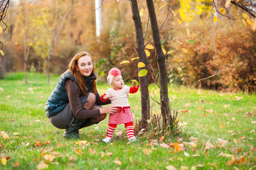 Fototapeta premium Mom and daughter are playing in the autumn park. A happy family.