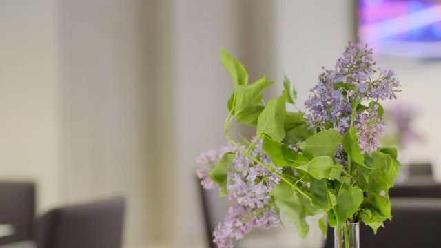 Office interior decor, bouquet of lilacs in a vase and books on the table in slow motion.