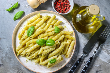 penne pasta with pesto sauce in plate on a wooden background. top view