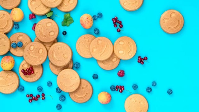 Stop motion food background. Delicious mini smile pancakes with berries  on blue surface, top view, dynamic scene, 4k video
