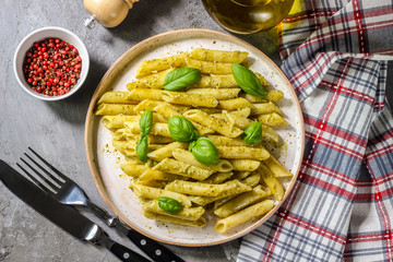 penne pasta with pesto sauce in plate on a wooden background. top view