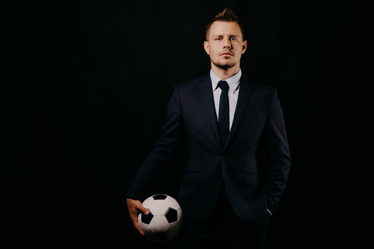 young handsome businessman holding a football on black background studio.
