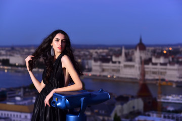 Fototapeta na wymiar Luxury woman in evening dress with view on city. Sexy girl in elegant dress. Modern life with princess in celebrity style. Fashion and beauty of business lady. Girl with glamour makeup.