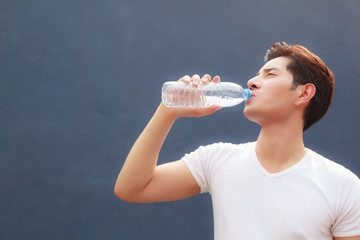 man holding clean fresh mineral water bottle with court background, drinking water outdoor under summer heat. Health care, Well being, Thirst Refreshment, Water Balance in body is medicine concept