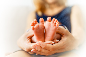 Sweet newborn baby's feet in woman's arms