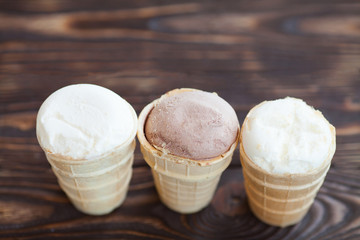 Homemade chocolate and vanilla ice cream in waffle cups on wooden background. Healthy summer food concept with copy space.