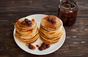 Delicious pancakes on wooden table with strawberry jam