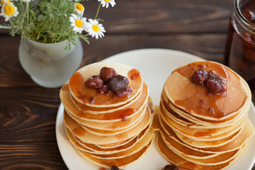 Pancakes with strawberry jam for a breakfast on a kitchen table. Sweet food and good mood
