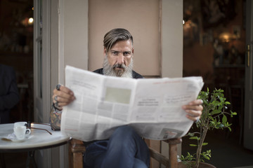 Attraktiver Mann sitzt in einer Coffeeshop, und liest Zeitung
