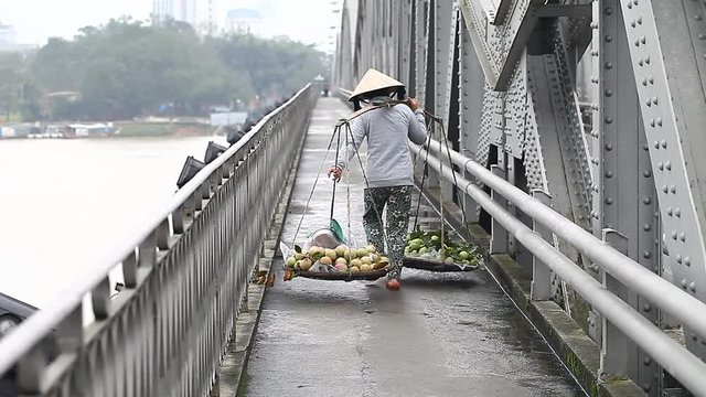Street vendor. Woman porter of fresh fruit in Vietnam