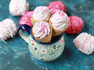 Homemade pink marshmallow with berries in waffle cones on a dark background. Selective focus.
