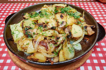 Fried potatoes with mushrooms in a frying pan