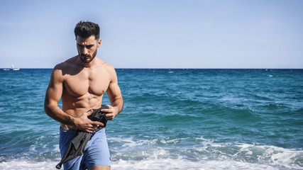 Handsome young man standing on a beach, feeling lonely and sad or simply relaxed, shirtless wearing boxer shorts