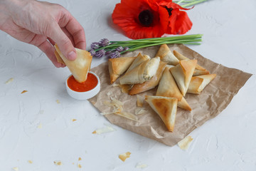 Man hand dip phyllo pie into tomato sauce
