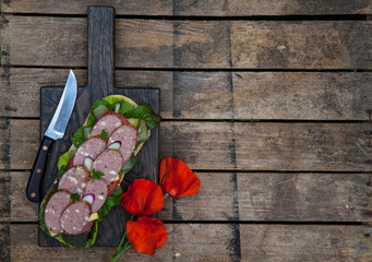 Sandwich with sausage slices, tomato and lettuce, top view