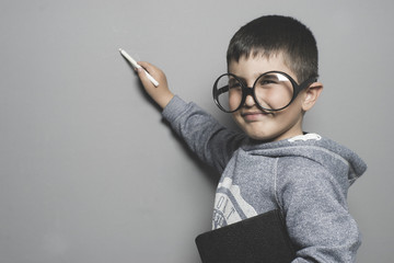 schoolboy, young student writing on a blackboard school with a book in hand and big glasses