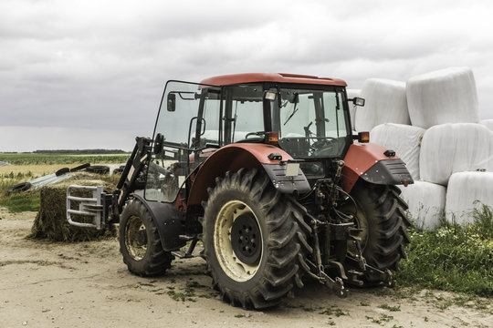 Unpacked from the membrane a silage bale and a tractor with a forklift.Near the pyramid of silage bales.Good food for cows.Dairy farm.Podlasie,Poland.