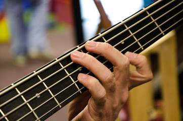 Closeup of photo of electric bass guitar player playing with hands