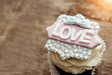 The cupcake with the word love on a brown background. Copy space