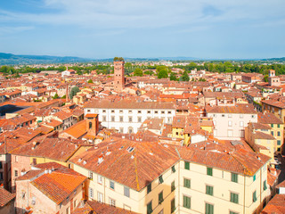 Fototapeta na wymiar Lucca cityscape lookout from Torre delle Ore. Red rooftops and Guinigi Tower, Lucca, Tuscany, Italy.