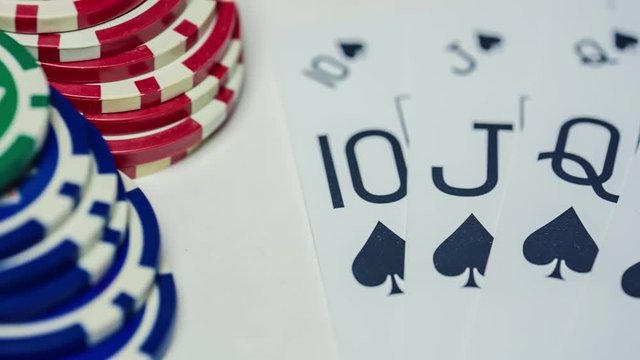 The player holds five playing cards in his hand. Royal Flash, card deck, poker royal flash on cards and poker chips on green casino table / on a black background. success in gambling. soft focus