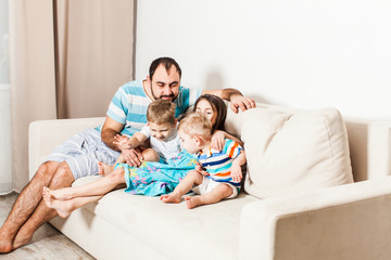 Man with his children sitting on the white sofa.