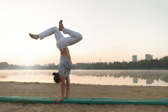Young athletic man doing yoga poses near the lacke