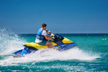 happy, excited family, father and son having fun on jet ski at summer vacation