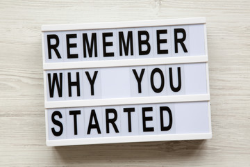 'Remember why you started' words on modern board over white wooden surface, from above. Top view, overhead, flat-lay.