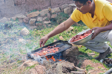 Native american man cooking the meat in the countryside.