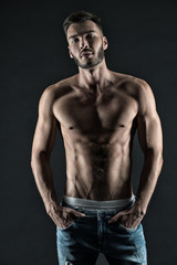 Fototapeta na wymiar Masculinity is sexy. Man muscular torso tense muscles veins put hands in pockets denim pants. Macho muscular chest looks attractive black background. Athlete with muscular body on confident face