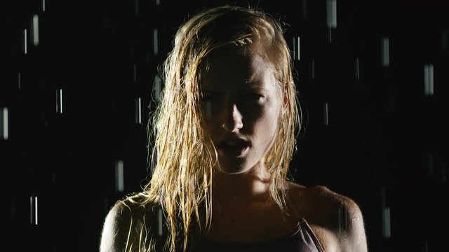 Athletic blond woman working out in the rain. Slow Motion