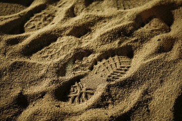 Footprint of worker's boot on yellow sand 