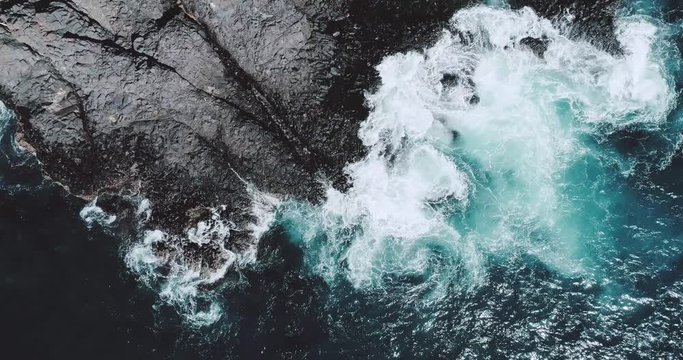 Aerial drone view of ocean waves crashing coastline cliff - video in slow motion
