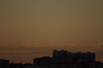 Naklejka premium Sunset over the city. Twilight and high-rise buildings landscape. Bright sunset over the horizon