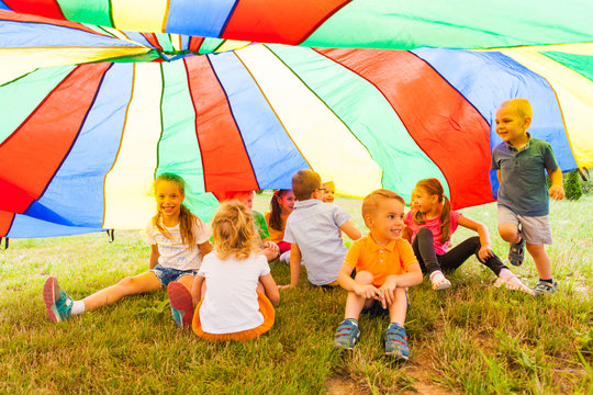 Laughing kids hide in multicolor shelter