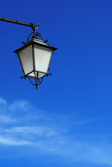 Fototapeta na wymiar Old fashioned wrought iron street lamp against blue sky and clouds (with copy space)