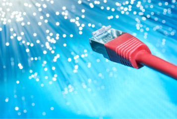 Closeup on the end of red optical fiber network cable on blue background