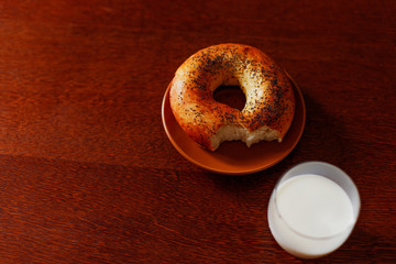 A delicious bagel and milk on a wooden table.