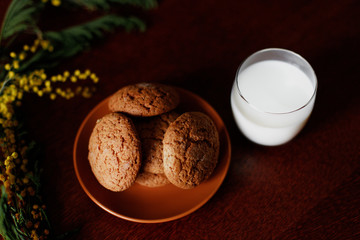 Oatmeal cookies and a glass of milk near the flowers.
