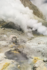 Thermal activity in the crater of the active volcano of White Island, Whakaari, off the Bay of Plenty coast, New Zealand. Yellow crystals of sulphur and boiling water in the foreground.