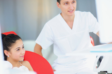 Young beautiful girl with a doctor in a dental office on a survey.