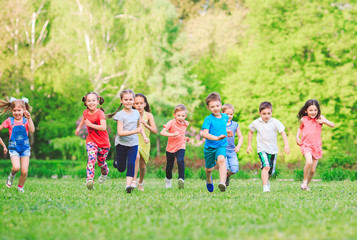 Fototapeta premium Many different kids, boys and girls running in the park on sunny summer day in casual clothes
