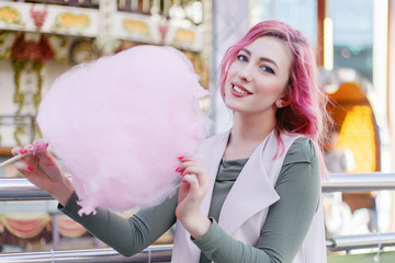 Portrait of pretty with pink hair girl with short haircut posing in amusement park on carousel...