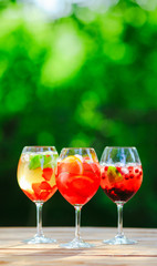 Summer cocktail. Fruit cocktail on green background. Citrus fruits, berries, strawberries, blueberries, mint, ice.